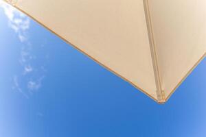 beach at the resort, view from below as if from a sunbed to an umbrella and clear blue sky. vacation at sea photo