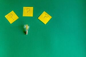light bulb and question marks on a beautiful dark green background, idea concept photo