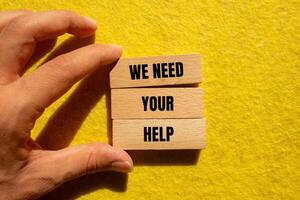 We need your help message written on wooden blocks with yellow background. Conceptual we need your help symbol. photo