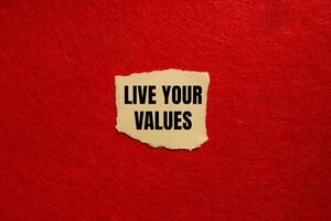 Live your values message written on ripped torn paper piece with red background. Conceptual live your values symbol. Copy space. photo