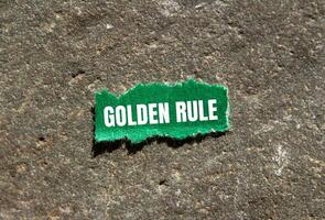 Golden rule message written on ripped green torn paper piece with stone background. Conceptual golden rule symbol. Copy space. photo
