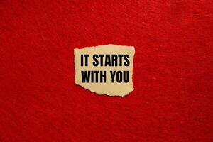 It starts with you message written on ripped torn paper piece with red background. Conceptual it starts with you symbol. Copy space. photo