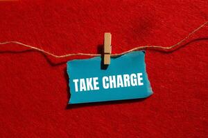 Take charge message written on ripped torn blue paper piece with red background. Conceptual take charge symbol. Copy space. photo