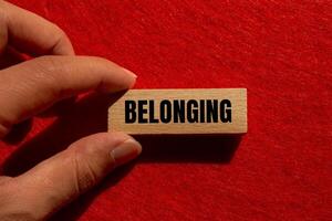 Belonging message written on wooden block with red background. Conceptual belonging symbol. Copy space. photo