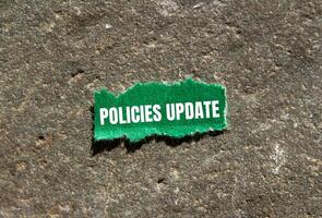 Policies update message written on ripped green torn paper piece with stone background. Conceptual policies update symbol. Copy space. photo