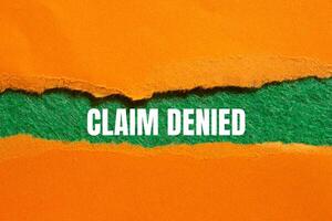 Claim denied message written on ripped torn orange paper with green background. Conceptual claim denied symbol. Copy space. photo