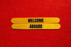 Welcome aboard message written on yellow wooden sticks with red background. Conceptual welcome aboard symbol. Copy space. photo