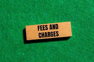 Fees and charges message written on wooden block with green background. Conceptual fees and charges symbol. Copy space. photo