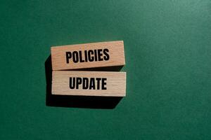 Policies update message written on wooden blocks with green background. Conceptual policies update symbol. Copy space. photo