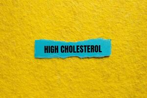 High cholesterol message written on ripped torn blue paper piece with yellow background. Conceptual high cholesterol symbol. Copy space. photo