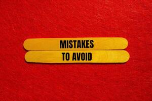 Mistakes to avoid message written on yellow wooden sticks with red background. Conceptual mistakes to avoid symbol. Copy space. photo