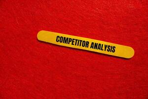 Competitor analysis message written on yellow wooden stick with red background. Conceptual competitor analysis symbol. Copy space. photo