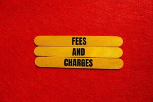 Fees and charges message written on yellow wooden sticks with red background. Conceptual fees and charges symbol. Copy space. photo