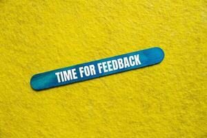 Time for feedback message written on blue wooden stick with yellow background. Conceptual time for feedback symbol. Copy space. photo