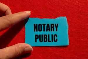 Notary public message written on ripped torn blue paper piece with red background. Conceptual notary public symbol. Copy space. photo