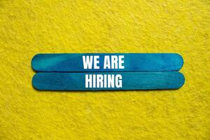 We are hiring message written on blue wooden sticks with yellow background. Conceptual we are hiring symbol. Copy space. photo