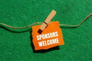 Sponsors welcome message written on ripped torn orange paper piece with green background. Conceptual sponsors welcome symbol. Copy space. photo