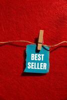 Best seller message written on ripped torn blue paper piece with red background. Conceptual best seller symbol. Copy space. photo