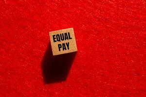 Equal pay message written on wooden cube with red background. Conceptual equal pay symbol. Copy space. photo