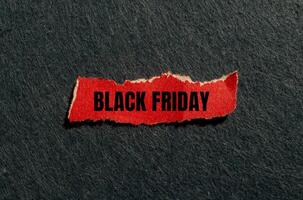 Black friday message written on ripped red torn paper piece with gray background. Conceptual black friday symbol. Copy space. photo
