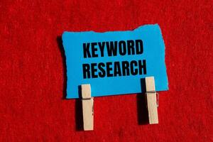 Keyword research message written on ripped torn blue paper piece with red background. Conceptual keyword research symbol. Copy space. photo