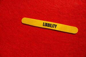 Liability message written on yellow wooden stick with red background. Conceptual liability symbol. Copy space. photo