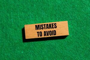 Mistakes to avoid message written on wooden block with green background. Conceptual mistakes to avoid symbol. Copy space. photo