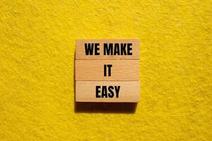 We make it easy message written on wooden blocks with yellow background. Conceptual we make it easy symbol. Copy space. photo
