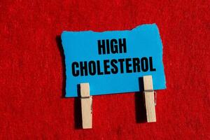 High cholesterol message written on ripped torn blue paper piece with red background. Conceptual high cholesterol symbol. Copy space. photo