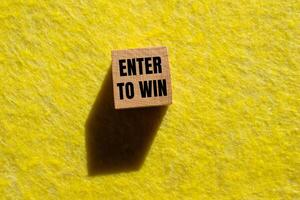 Enter to win message written on wooden cube with yellow background. Conceptual enter to win symbol. Copy space. photo