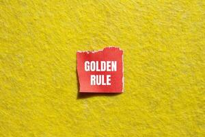 Golden rule message written on ripped torn red paper piece with yellow background. Conceptual golden rule symbol. Copy space. photo