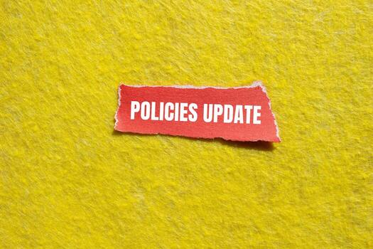 Policies update message written on ripped torn red paper piece with yellow background. Conceptual policies update symbol. Copy space. photo