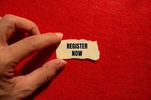 Register now message written on ripped torn paper piece with red background. Conceptual register now symbol. Copy space. photo
