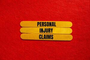 Personal injury claims message written on yellow wooden sticks with red background. Conceptual personal injury claims symbol. Copy space. photo