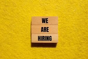 We are hiring message written on wooden blocks with yellow background. Conceptual we are hiring symbol. Copy space. photo