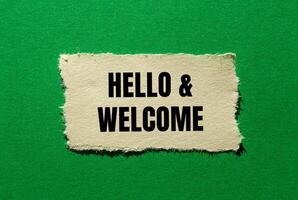 Hello and welcome message written on ripped torn paper piece on green background. Conceptual hello and welcome symbol. Copy space. photo