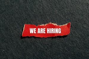 We are hiring message written on ripped red torn paper piece with gray background. Conceptual we are hiring symbol. Copy space. photo
