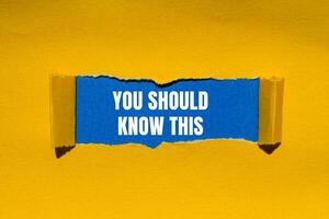 You should know this message written on ripped torn yellow paper with blue background. Conceptual you should know this symbol. Copy space. photo