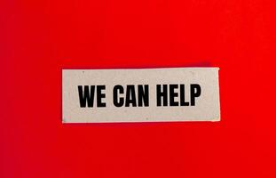 We can help message written on paper piece with red background. Conceptual we can help symbol. Copy space. photo