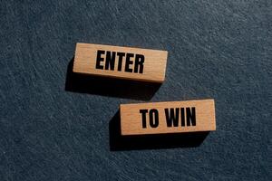 Enter to win message written on wooden blocks with gray background. Conceptual enter to win symbol. Copy space. photo
