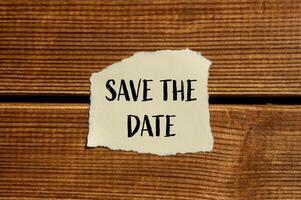 Save the date message written on ripped torn paper with wooden background. Conceptual save the date symbol. Copy space. photo