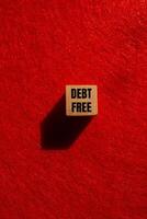 Debt free message written on wooden cube with red background. Conceptual debt free symbol. Copy space. photo