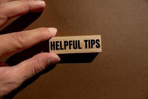 Helpful tips message written on wooden block with brown background. Conceptual helpful tips symbol. Copy space. photo
