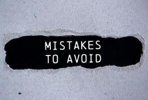 Mistakes to avoid message written on ripped torn gray paper with black background. Conceptual mistakes to avoid symbol. Copy space. photo