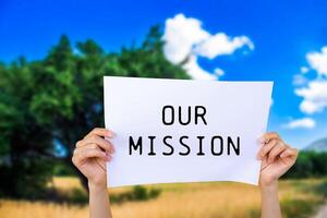 Our mission message written on white paper with nature background. Conceptual our mission symbol. Copy space. photo