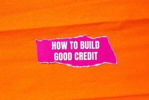 How to build good credit message written on ripped torn pink paper with orange background. Conceptual how to build good credit symbol. Copy space. photo