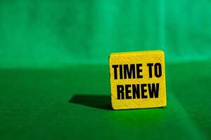 Time to renew message written on yellow wooden cube with green background. Conceptual time to renew symbol. Copy space. photo
