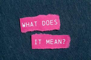 What does it mean question written on ripped torn pink paper pieces on gray background. Conceptual what does it mean question symbol. Copy space. photo