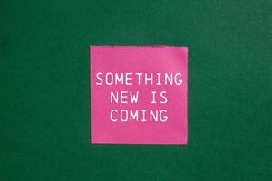 Something new is coming message written on ripped torn pink paper on green background. Conceptual something new is coming symbol. Copy space. photo