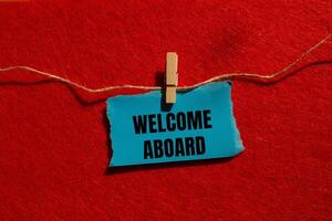 Welcome aboard message written on ripped torn blue paper piece with red background. Conceptual welcome aboard symbol. Copy space. photo